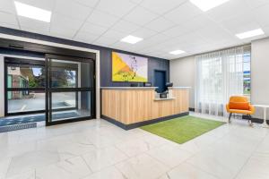 un bureau avec une salle d'attente avec une télévision et une chaise dans l'établissement Spark by Hilton Essex Junction, à Essex Junction