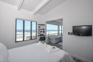 a bedroom with a bed and a tub and a tv at Sandbanks Villa in Yzerfontein