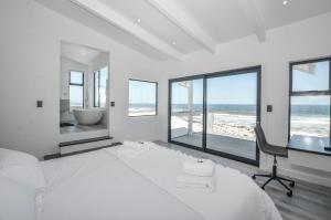 a bedroom with a bed and a desk with a desk at Sandbanks Villa in Yzerfontein +55 photos