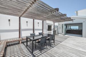 a patio with a table and chairs on a deck at Sandbanks Villa in Yzerfontein