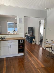a kitchen with white cabinets and a wooden floor at Riverview Cottage in Dunbogan