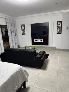 a living room with a black couch and a tv at WeMvula Guesthouse in Mtubatuba