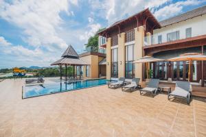 Una piscina con sillas y sombrillas al lado de un edificio. en Leva Boutique Hotel, en Ko Samui