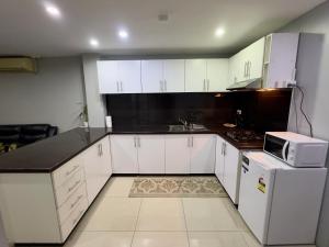 une petite cuisine avec des armoires blanches et un micro-ondes dans l'établissement Cloud Apartments 2 Bedroom in Lautoka CBD, à Lautoka 3 autres photos