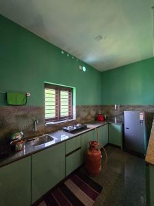 a green kitchen with a sink and a refrigerator at Nature's Frame Residency in Varkala