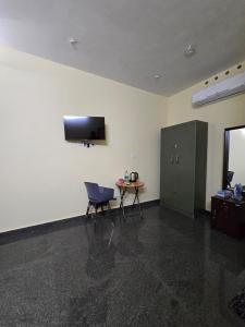 a room with a chair and a table and a television at Nature's Frame Residency in Varkala