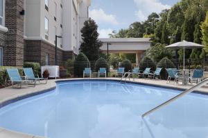 a large blue swimming pool with chairs and umbrellas at Hampton Inn & Suites Huntersville in Huntersville