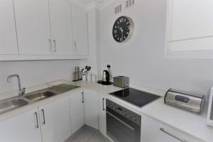 a kitchen with white cabinets and a clock on the wall at Sea Lodge 61 in Durban