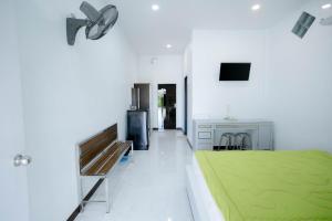 a white room with a green bed and a kitchen at Thongkon Hotel in Surin