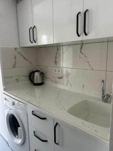a kitchen with white cabinets and a washing machine at DİDİM Ege Apart in Didim