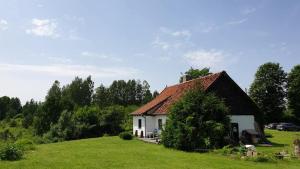 a small white house on a grassy hill at Na Żurawim Wzgórzu in Pasym