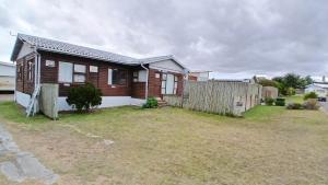 a small house with a fence in the yard at David Bongers Still Bay Holiday Home in Stilbaai