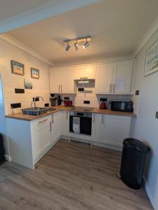 a kitchen with white cabinets and a sink at 246, Belle Aire, Hemsby - Two bed recently renovated chalet, sleeps 5, free Wi-Fi, pet friendly, bed linen and towels included with onsite entertainment in Great Yarmouth +15 photos