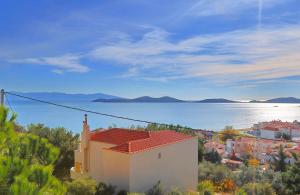 a white building with a red roof next to the water at Summer House Nea Peramos in Néa Péramos
