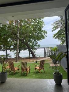 three chairs and a table with a view of the ocean at Bloom Beach Villa in Batigama