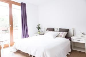 a white bedroom with a white bed and a window at Residence Mariagrazia - Kärnten Card im Sommer inklusive in Bad Kleinkirchheim