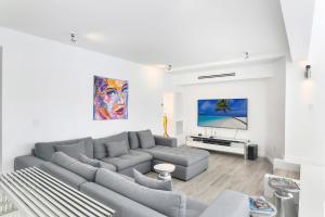 een woonkamer met een grijze bank en een flatscreen-tv bij Villa Moonlight Haven in Miami Beach