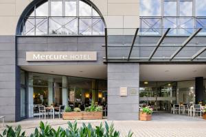 埃施伯恩的住宿－Mercure Hotel Frankfurt Eschborn Süd，一家配有桌椅的美利坚酒店前的商店