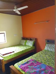 two beds in a room with orange walls at Tunga Teera in Sringeri