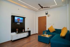 een woonkamer met een blauwe bank en een flatscreen-tv bij Evaara By The Ganges in Haridwār
