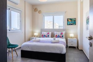 a bedroom with a large bed with two windows at Ondo 2-Bedroom Apartment in Larnaca +10 photos