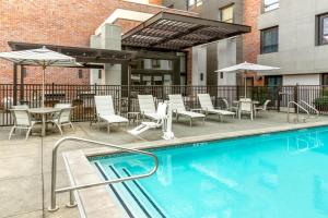 a swimming pool with chairs and tables and umbrellas at Homewood Suites by Hilton Palo Alto in Palo Alto