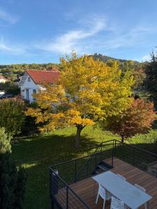 eine Holzterrasse mit einer weißen Bank und einem Baum in der Unterkunft L'aurore des Volcans in Romagnat