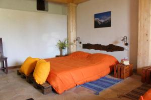 a bedroom with a large bed with an orange comforter at Agriturismo La Caraffara sull'Etna in Puntalazzo