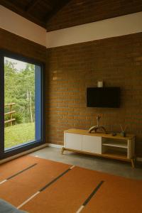 a living room with a television on a brick wall at Sitio Dona Bela - Rio da Prata in Joinville