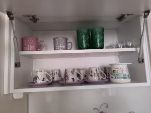 a row of mugs on a shelf in a kitchen at My Place in Lukavica +3 photos
