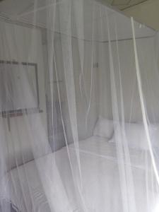 a bed covered in white curtains in a room at Cascade Vally in Ella