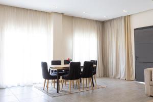 une salle à manger avec une table et des chaises noires dans l'établissement Golden 4BR Pool Villa by Travelholic, au Caire