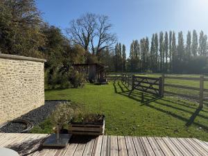 a garden with a fence and a wooden deck at Studio lumineux avec terrasse et jardin proche de Caen 