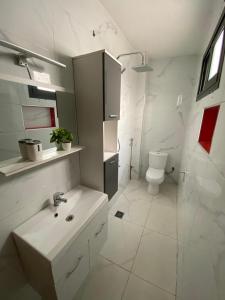 a white bathroom with a sink and a toilet at La Belle Escale in Pikine