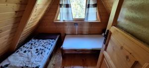 a small room with a bed and a window at Uroczysko Domki in Zarzecze