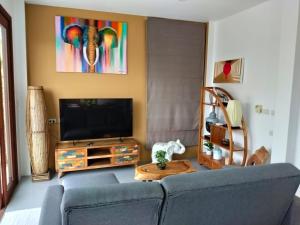 a living room with a blue couch and a tv at VILLA JADE orchid life residence in Koh Samui