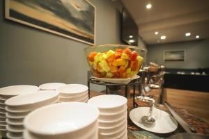 a bowl of fruit on a table with white plates at JC Residency in Kodaikānāl