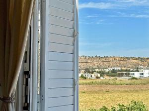 a window view of a field from a house at 5-Min Walk to Beach - Bright 2-BR Home with Private Garden & Sunset Views in Voroklini