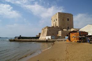 a building on the beach next to the water at Calipso Suite Room in Pozzallo
