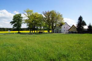 a white house in a field of green grass at Landpension Bielatal - Raum in Raum