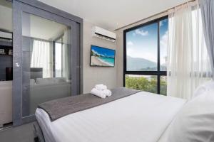 ein Schlafzimmer mit einem großen weißen Bett und einem Fenster in der Unterkunft Tropics Kamala CTG P615 - Corner 1 BR Apt Mountain view in Kamala Beach + 13 Fotos