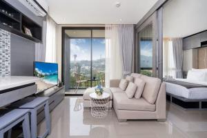 ein Wohnzimmer mit einer Couch und einem Bett in der Unterkunft Tropics Kamala CTG P615 - Corner 1 BR Apt Mountain view in Kamala Beach