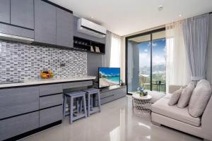 eine Küche mit einem Sofa und einem Fernseher in einem Zimmer in der Unterkunft Tropics Kamala CTG P615 - Corner 1 BR Apt Mountain view in Kamala Beach