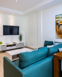 Una sala de estar con un sofá azul y un televisor. en CasaNova Airport Suites, en Accra