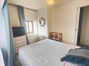 a bedroom with a bed and a flat screen tv at Le studio - La maison de la côte des légendes in Plounéour-Trez