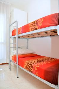a bedroom with two bunk beds with red sheets at Residence Itaca in Bibione
