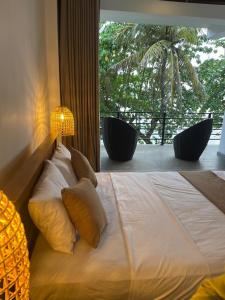 a bedroom with a large bed with a large window at Bloom Beach Villa in Batigama