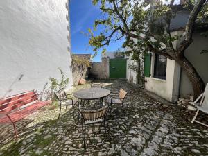 eine Terrasse mit Tisch und Stühlen und einem Baum in der Unterkunft Maison de la Beureliere in Sainte-Marie-de-Ré