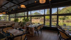 Un restaurante con mesas y sillas y grandes ventanales. en Verona Ağva, en Sile