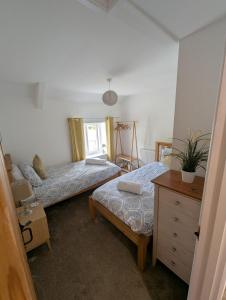 a bedroom with two beds and a dresser and a window at Primrose cottage - Upper cwmbran in Pontnewydd